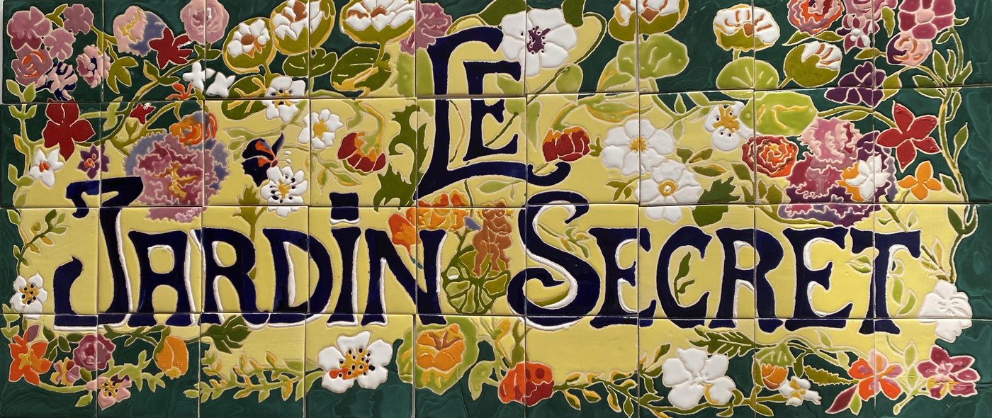 Panneau « Le Jardin Secret » en céramique, lettres Art nouveau bleu nuit sur fond jaune, bordure de fleurs
